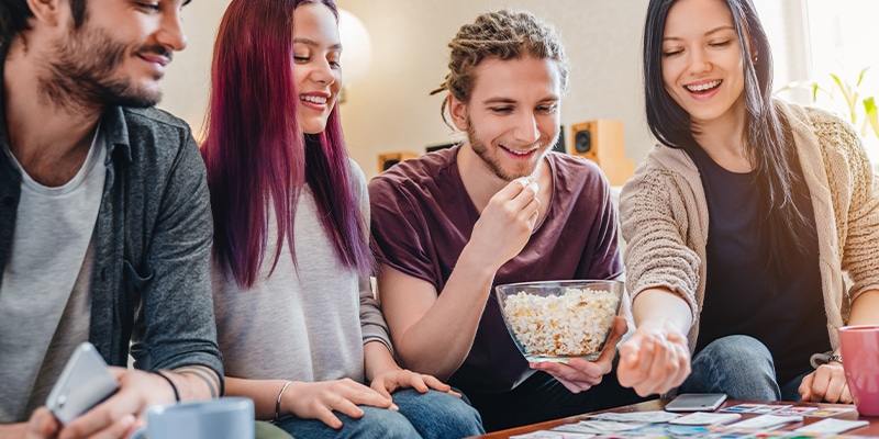 Group Of Friends Eating Popcorn While Playing Card Game